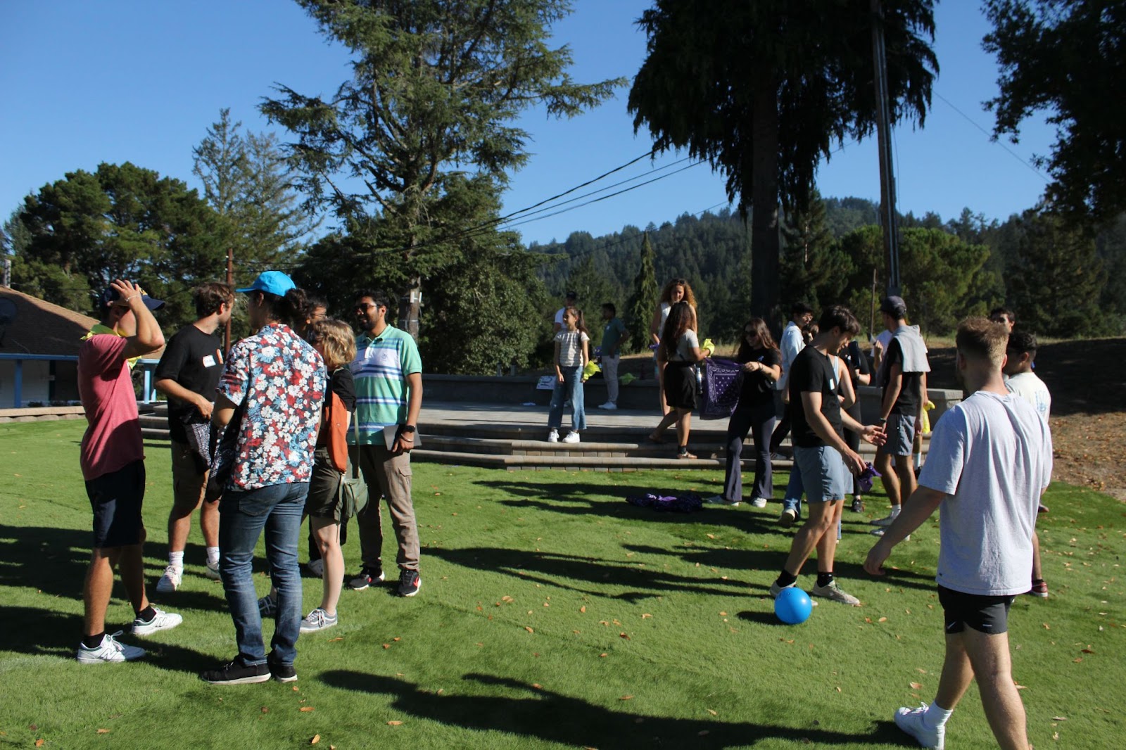 Residents at the retreat are speaking in groups on the lawn. They are engaging or looking to engage in recreational sporty activities.