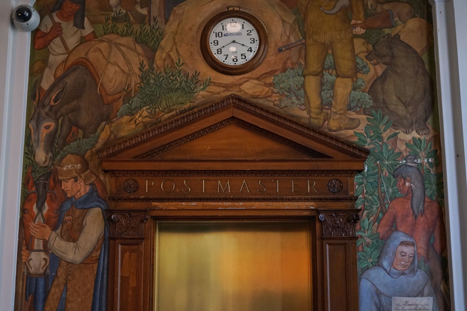 A detailed mural over the wall above an elevator. It depicts a complex scene. There is one bear on the right side. 
