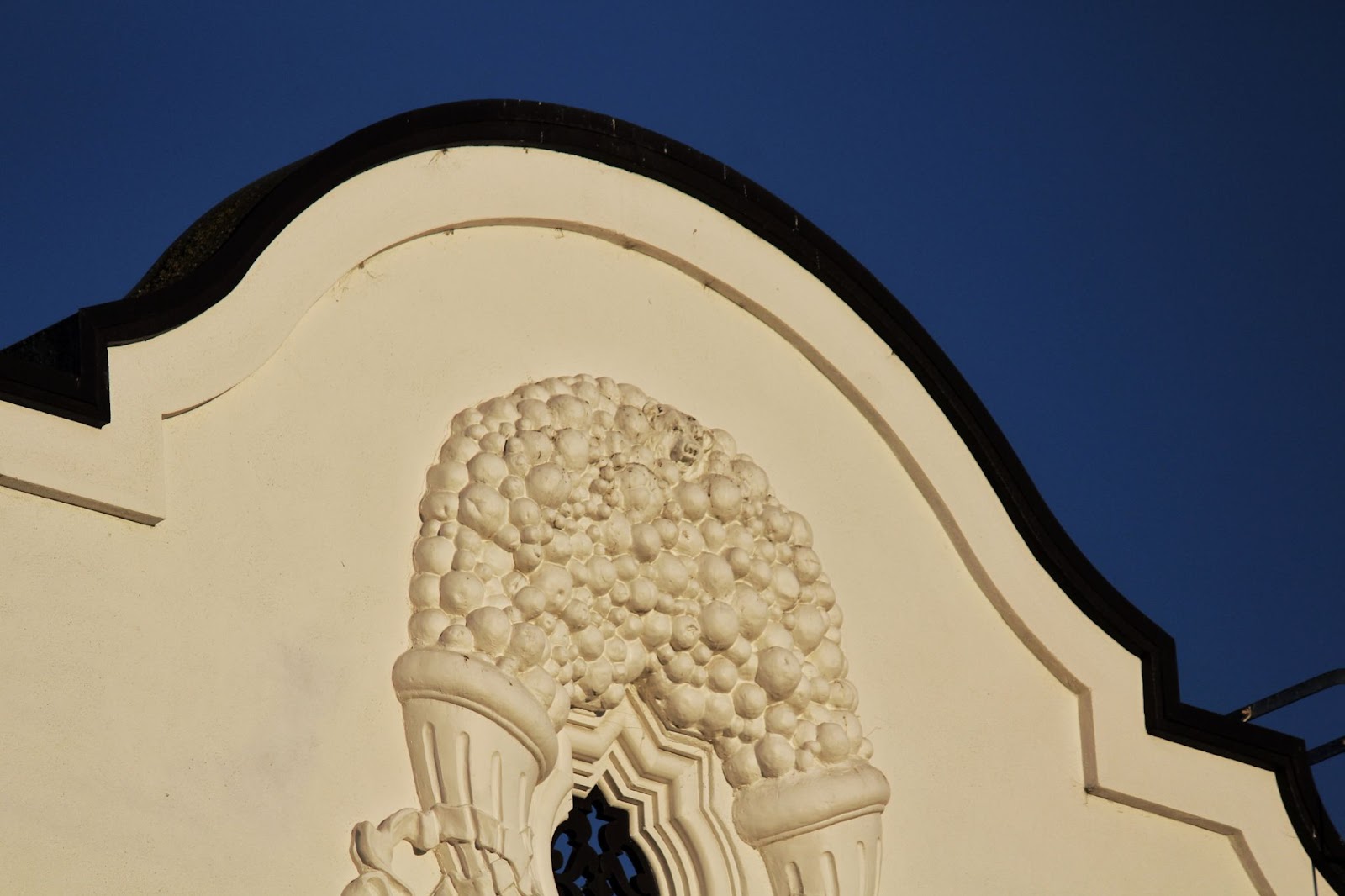 A bubbly relief embellishment above a window of the Granada building. There is a small bear head at the center of the top of the embellishment. 