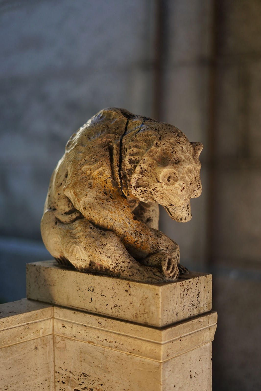 A bear statue on the right end of a bench. 