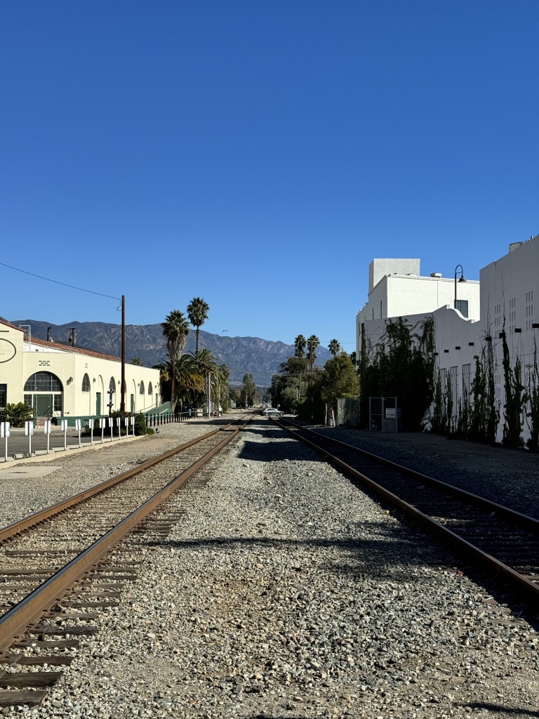 Straight view of train tracks with white buildings on either side.