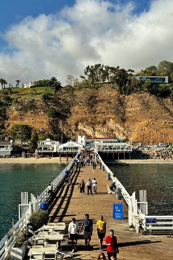 A view of the entrance of a pier with rocky hills in the backdrop.